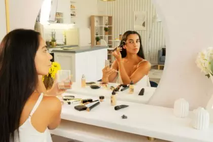 brunette woman with long straight dark hair and clean skin doing make up routine