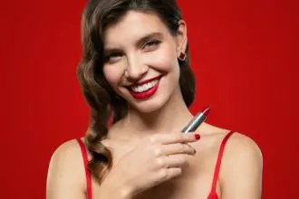 Portrait of elegant woman with red lips and evening makeup holding lipstick